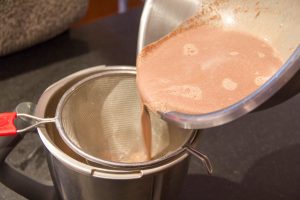 Versez le chocolat chaud dans le blendeur en le filtrant