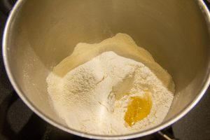Ajoutez le sel, l’œuf battu à la farine et versez l'eau et la levure diluée sur la farine