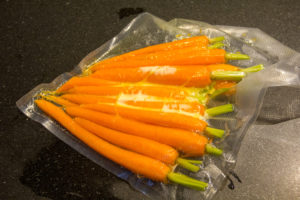 Mettez les carottes fanes sous vide avec le zeste de l'orange et une noix de beurre