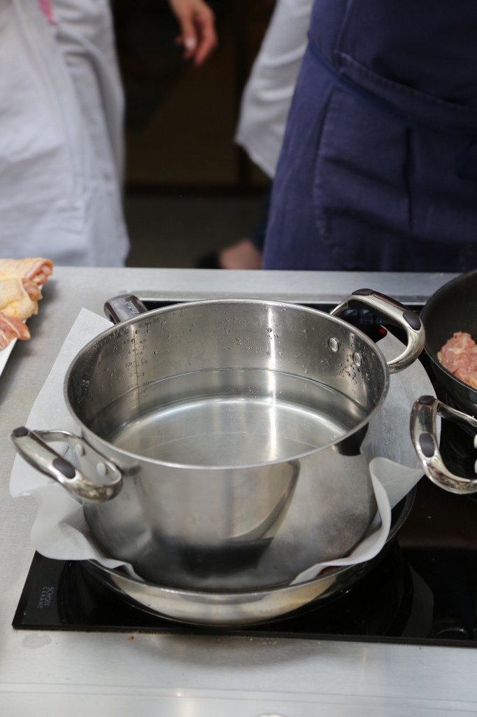 Déposez la casserole d'eau sur la feuille de cuisson protégeant le poulet