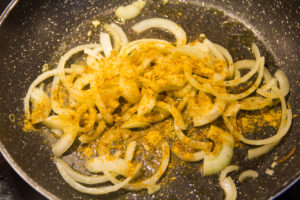 Faites revenir les tranches d'oignon dans une poêle avec un peu d'huile d'olive et du curry et une pincée de 